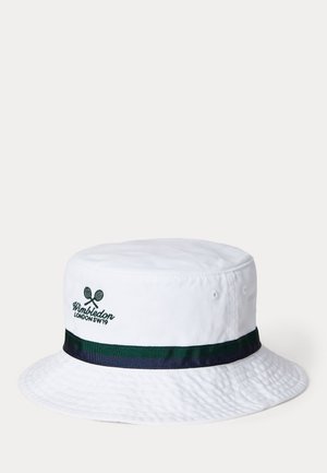 Baltas medvilninis skrybėlaikys su tekstūruotu paviršiumi. Papuoštas žalia ir tamsiai mėlyna juostele ir siuvinėtu "Wimbledon" logotipu.