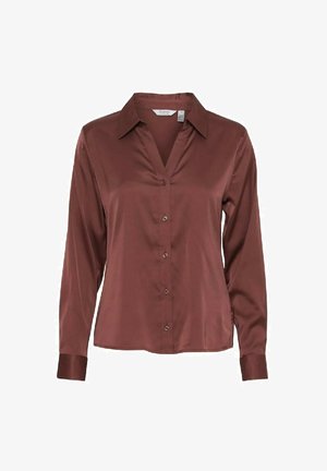 Camicia lunga in satin marrone con colletto, chiusura frontale con bottoni e una leggera lucentezza. Presenta un collo a V e polsini aderenti.