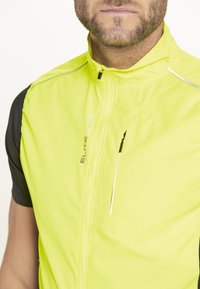 Limegrüwest Fahrradweste mit hohem Kragen, Frontreißverschluss, schwarzen kurzen Ärmeln und reflektierenden Details für Sichtbarkeit. Leichtes Material.