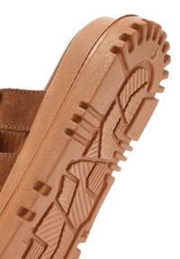 Scarpa scamosciata color sabbia con suola in gomma, caratterizzata da una trama e un disegno per garantire trazione. Tra i dettagli spiccano le scanalature e le onde per migliorare la presa.