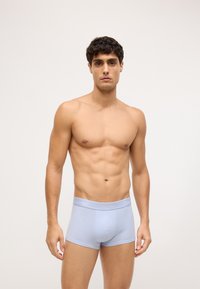 Boxeri de culoare albastru deschis, cu o textură moale, având un logo Calvin Klein pe banda elastică, design potrivit și material neted.