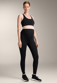 Fekete sportmelltartó és magas derekú leggings rugalmas anyagból. Az öltözék sima textúrával és minimális dizájnnal rendelkezik.