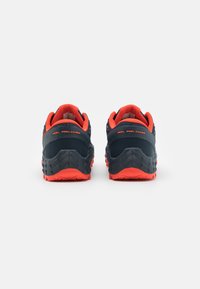 Chaussures de sport bleu foncé avec des accents orange vif. Talon texturé pour une meilleure stabilité, présentant une semelle robuste pour une adhérence améliorée.