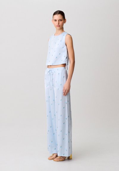 Top corto azzurro chiaro e pantaloni a gamba larga abbinati con piccoli motivi floreali. Tessuto liscio con vestibilità rilassata e vita elastica.