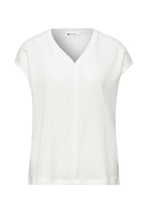 Blouse blanche à manches courtes en tissu texturé, col en V et couture verticale décorative au centre devant.