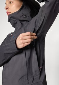 Dark gray waterproof jacket with a high collar, front zipper, and side zip pocket, featuring a smooth texture and adjustable drawstring.