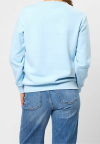 Himlen blå sweatshirt med rund halsringning och långa ärmar, tillverkad av mjukt tyg, kombinerad med högmidjade blå jeans med bakfickor.