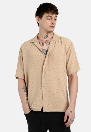Short-sleeved, beige button-up shirt with colorful dot pattern, lightweight fabric, straight cut, and a soft texture. Crafted for comfort.
