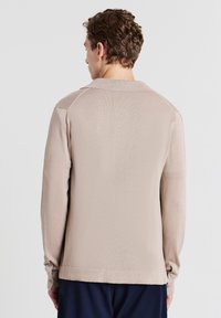 Khaki-Strickpullover mit Kragen, langen Ärmeln und geknöpften Manschetten. Glatte Textur mit einem leicht gerippten Muster.