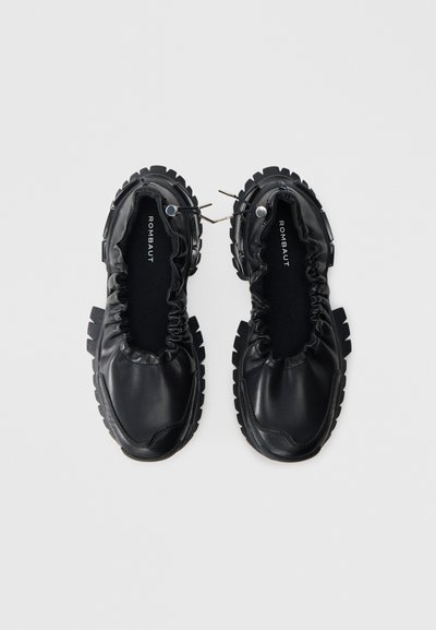 Černé nazouvací boty s kulatou špičkou, s elastickými detaily se sklady, strukturovanou podrážkou, logem na vložce a kontrastními gumovými akcenty na podrážce.