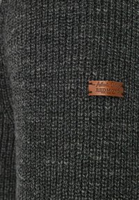 Dunkelgrauer gestrickter Pullover mit einem strukturierten Muster. Ein braunes Lederetikett mit "Authentic Clothing Redmond" ist auf dem Stoff angebracht.