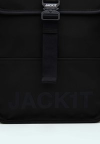 Zaino nero realizzato in materiale resistente, con un grande logo in rilievo "JACK1T", dotato di una chiusura sicura e di un design elegante.