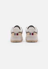 Sneaker con una toma in pelle bianca, accenti in suede beige e dettagli neri; con un logo a strisce sul tallone e una suola testurizzata.