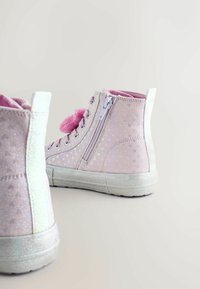 Rosa High-Top-Sneaker mit einer strukturierten, schimmernden Oberfläche, herzgemusterten Akzenten und einem seitlichen Reißverschluss. Gummisohle mit weicher rosa Innenauskleidung.