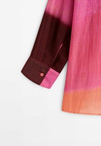 Chemise à manches longues avec un dégradé de couleurs passant d'un bordeaux foncé au rose et se terminant en orange au bas de l'ourlet.