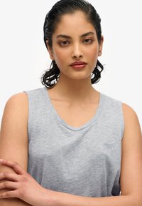 Top grigio senza maniche con scollatura rotonda e texture morbida. Presenta un piccolo logo sul petto, progettato per un look casual.
