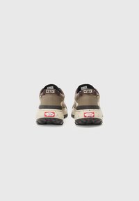 Zapatillas marrones y beige con una parte superior texturizada, una entresuela crema moteada y suelas de goma negras. Presentan acentos de marca en el talón.