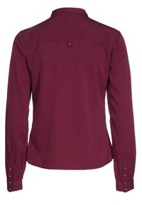 Camicia a maniche lunghe color bordeaux con colletto abbottonato, dotata di spallina dietro e dettagli con bottoni sui polsini. Tessuto liscio e leggero.