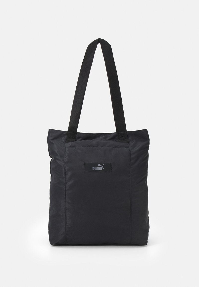 Black nylon tote bag with short, sturdy straps; features a textured surface and a small logo patch on the front. Simple square design.