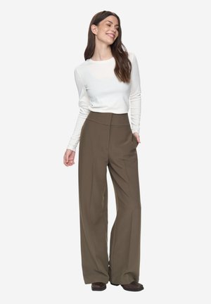 Pantaloni verde măsliniu cu croială largă și talie înaltă, asortați cu un top alb cu mâneci lungi, mulat. Material neted și design structurat.