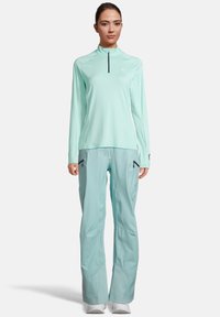 Lichte, mints groene top met lange mouwen en een halvemaan-rits kraag, gecombineerd met bijpassende mints groene broek met ritszakken.