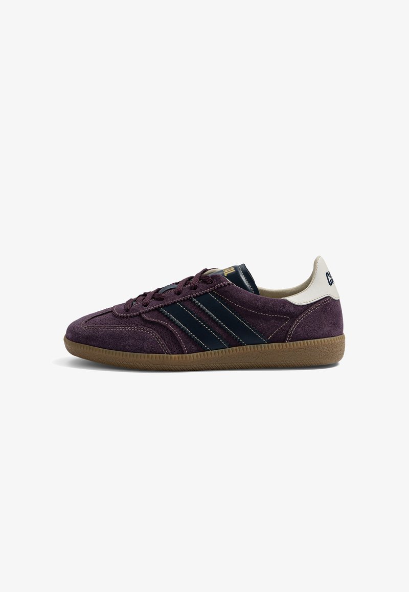 Baskets en daim violet avec semelle en caoutchouc marron, bandes latérales noires, languette blanche au talon et lacets, vues de côté gauche.