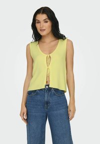 Geel geribbeld crop top met een diepe V-halslijn en strikdetail aan de voorkant, gecombineerd met hoogwaardige blauwe spijkerbroek.
