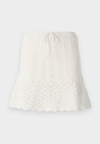 Jupe tricotée blanche avec une taille ajustée et un cordon de serrage. Présente un design texturé avec un ourlet en forme de scallop et des motifs en losange ouverts.