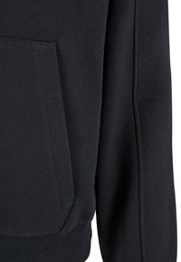 Primer plano de la tela de una sudadera negra mostrando el bolsillo frontal, la manga y el dobladillo acanalado con detalles visibles de costura.