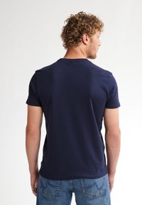 Marineblå bomulds T-shirt med rund hals og korte ærmer, med et ensfarvet design og almindelig pasform, båret med denim jeans.