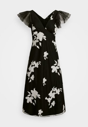 Černé šaty s bílou květinovou výšivkou, vykrojeným dekoltem a průsvitnými černými tylovými rukávy. A-liniová silueta s délkou po kolena.