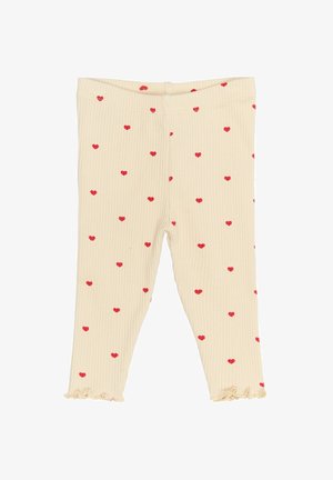 Igle helanke u krem boji s razbacanim uzorcima crvenih srca; imaju naborane rubove na člancima.