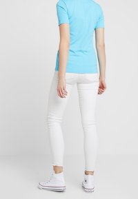 Vaaleansininen istuva t-paita, lyhyet hihat, yhdistetty valkoisiin kapeisiin farkkuihin ja valkoisiin korkeakorkoisiin lenkkareihin. Yksinkertainen, rento asu.