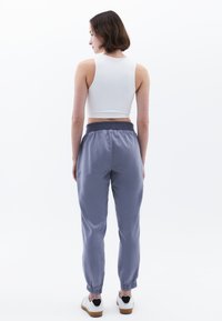 Lichtgrijze joggers met elastische boorden en tailleband, gecombineerd met een wit aansluitend tanktop. Soepele stof met minimale details.