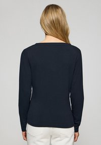 Camicia a maniche lunghe blu navy con un ampio scollo quadrato e un taglio aderente. Il tessuto appare liscio con una leggera elasticità.