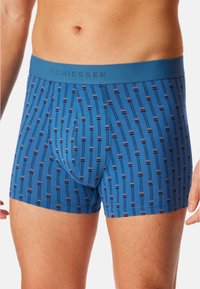Blaue gemusterte Boxershorts mit einem elastischen Bund und dem "Schiesser"-Logo. Das Design hat vertikale Linien mit kleinen Akzenten in dunklen Farben.