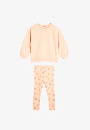 Pfirsichfarbener Sweatshirt mit Rippärmeln und Rundhalsausschnitt, kombiniert mit Rippleggings, die ein florales Muster in passenden Pfirsichtönen aufweisen.