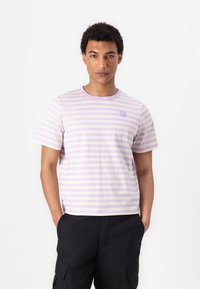 Dryžuota trumpa rankovė t-shirt šviesiai purpurinės ir baltos spalvos, su apvalia iškirpte ir mažo purpurinio gėlės grafiku ant krūtinės.