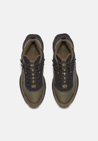 Chaussures de randonnée avec une tige en maille noire, des accents vert olive, des surfaces texturées, une semelle en caoutchouc et des œillets renforcés pour les lacets.