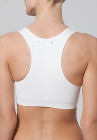 Witte sportbh met een racerback ontwerp, zachte stofstructuur en minimalistische branding in lichtgrijs aan de achterkant.