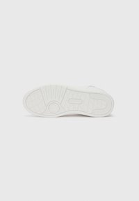 Hvit sneakersåle med et teksturert gummidesign. Inneholder sirkulære og lineære mønstre, preget merkevare og en flat profil.