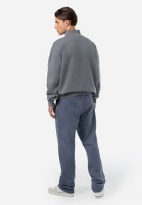 Grå bomullsgenser med høy krage og avslappet passform, parret med matchende grå joggebukser. Begge har en jevn tekstur og minimalistisk design.