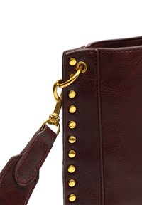 Borsa a mano in finta pelle colore bordeaux con hardware dorato, caratterizzata da una fila di borchie e una tracolla rimovibile. Superficie testurizzata con cuciture visibili.