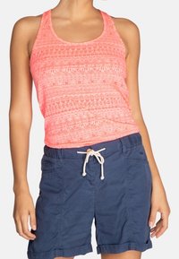 Top sin mangas de coral brillante con una textura de patrón intrincado, combinado con pantalones cortos azul marino con cintura elástica y dobladillos enrollados.