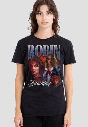 Woman wearing black T-shirt featuring three images of Robin Buckley character from a TV show, with large text "ROBIN" above and "Buckley" below.