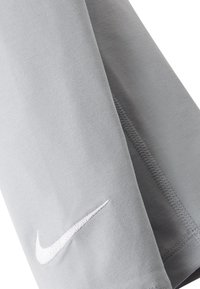 T-shirt grigio Nike con maniche corte, orlo cucito e un piccolo logo bianco sulla manica sinistra. Tessuto di cotone morbido e texturizzato.