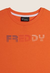 Camiseta de algodón naranja con cuello redondo y texto gráfico texturizado "FREDDY" en patrones de píxeles de colores: azul, rojo y blanco.