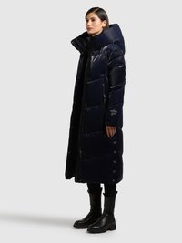 Lang dunjakke i marineblå, skinnende materiale med høj krave, lynlås foran og sidelommer. Har kompakt quiltet mønster og trykknaplukninger.