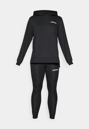 Sort hoodie med en frontlomme og hvidt Adidas-logo; parret med sorte leggings med Adidas-logoet på hoften. Blød stoftekstur.