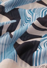 Tissu à motif abstrait présentant des rayures ondulées bleues, des sections noires et crème. Texture douce avec des plis drapés.